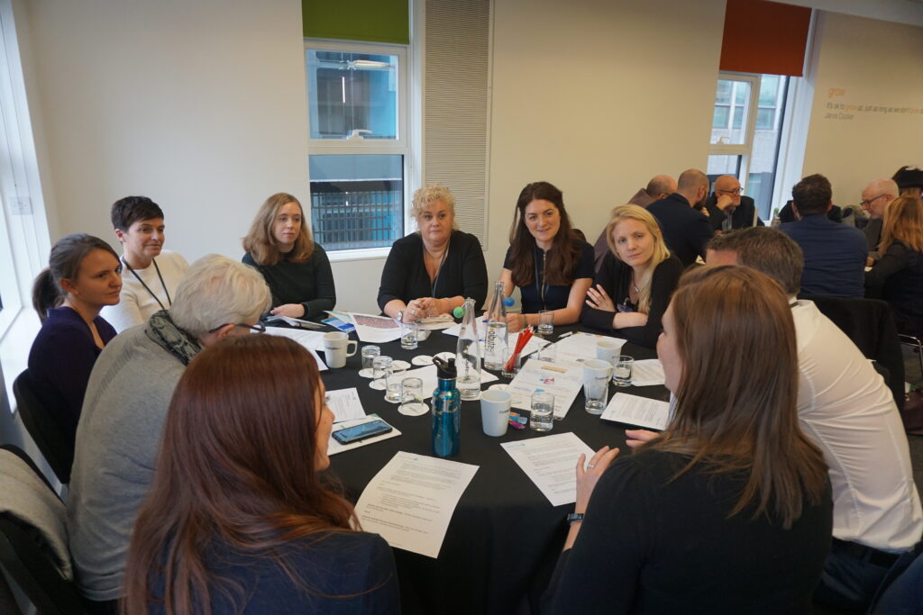 A group of people sitting around a circular table, talking.