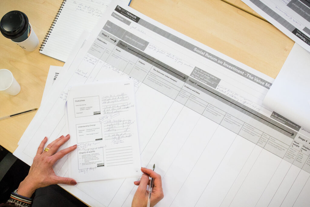 A pair of hands holding a pen and writing notes on a large piece of paper