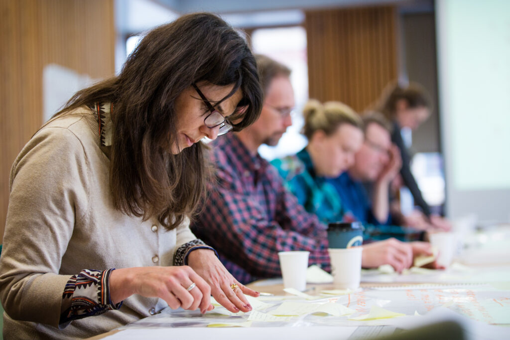 Four people sitting at a table looking at papers