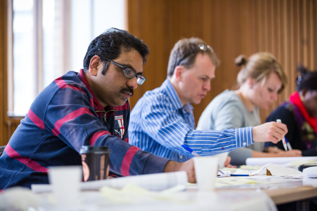 Three people sitting at a table writing